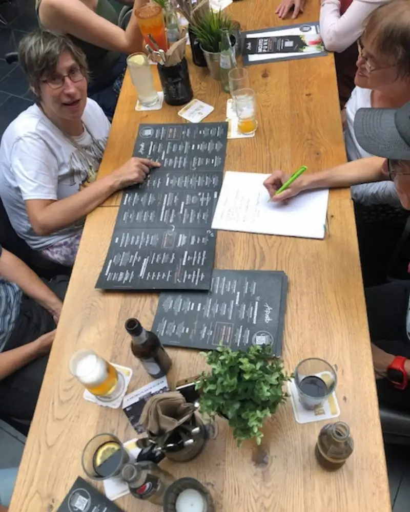Mehrere Personen sitzen an einem langen Tisch und schauen in Speisekarten
