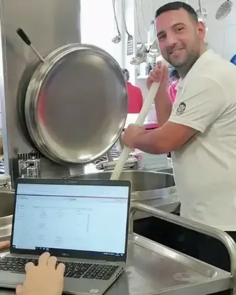 Ein Mann am Herd, im Vordergrund ein Laptop