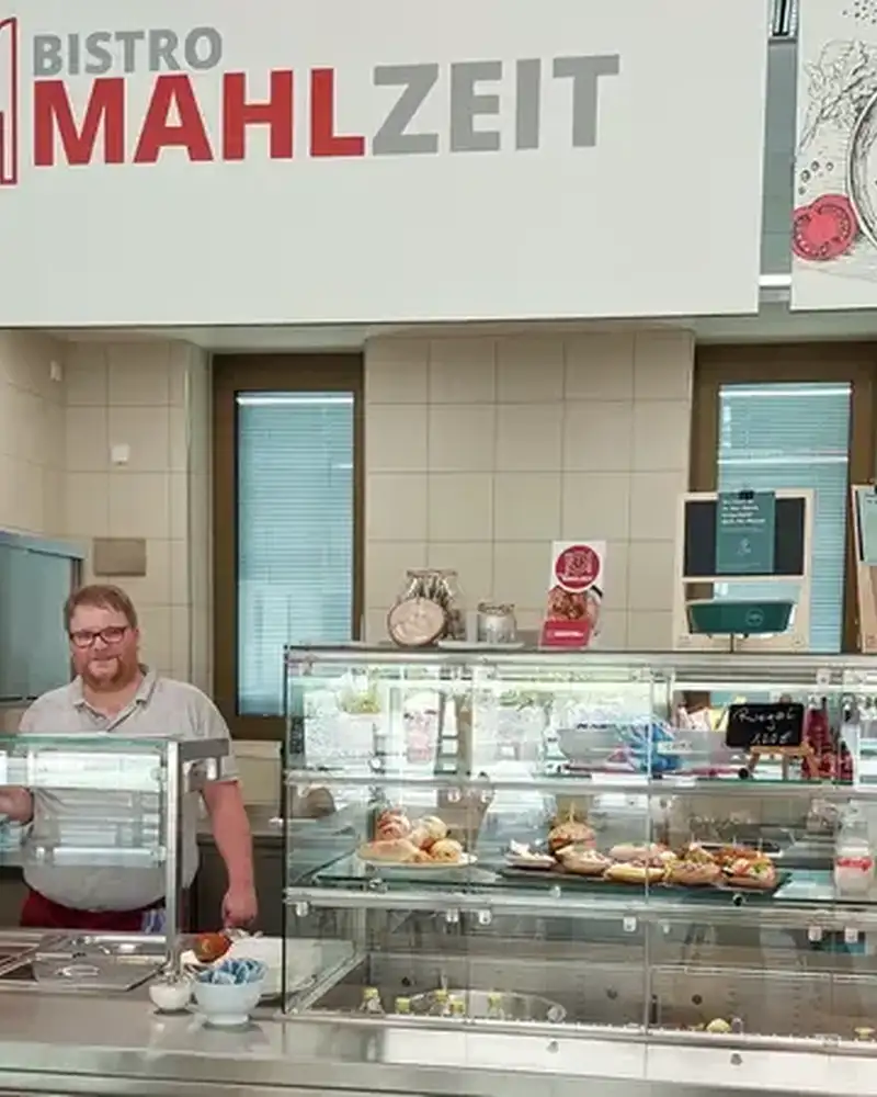 Drei Personen stehen hinter der Theke des Bistros Mahlzeit
