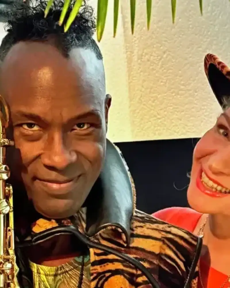 Eine weiße Frau mit Tigerfell-Hut und ein schwarzer Mann mit Tigerkostüm und Saxophon.