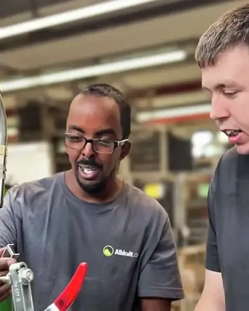 Zwei Männer arbeiten an einem Schweißgerät in einer Werkstatt.