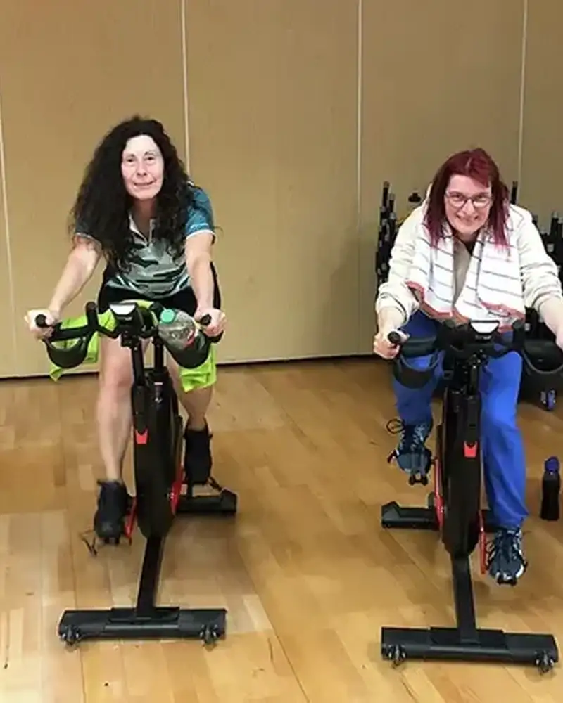 Vier Personen mit und ohne Behinderung sitzen auf einem Sporttrainingsgerät