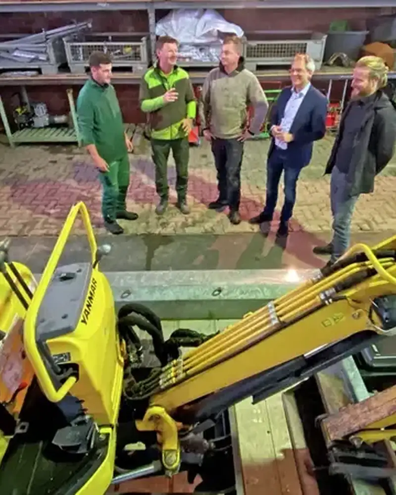 Vier Männer stehen in einer Halle mit landwirtschaftlichen Geräten