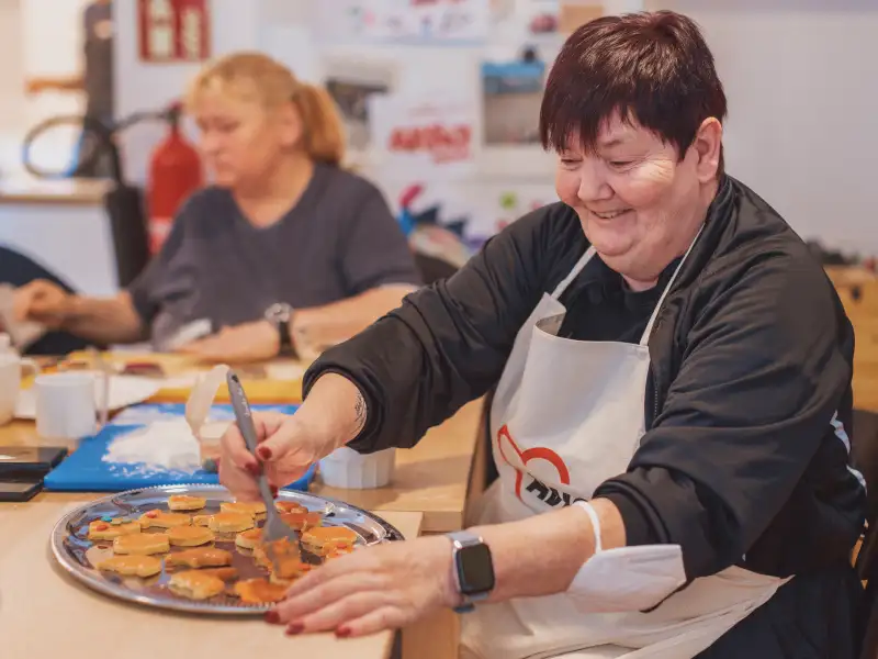 Eine Frau bepinselt Plätzenteiglinge mit Eigelb.