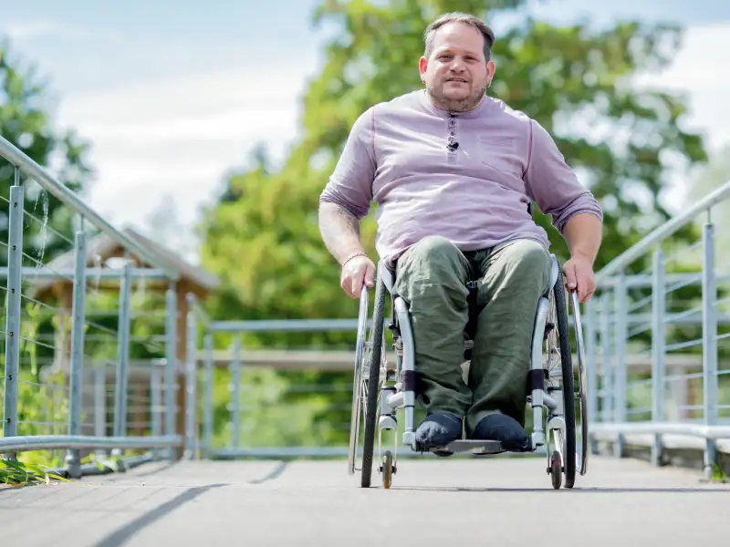 Ein Mann im Rollstuhl rollt eine Rampe hoch.