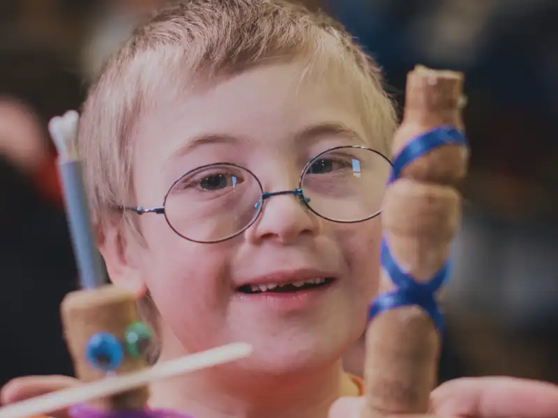 Ein Junge mit Downsyndrom zeigt selbstgebastelte Figuren