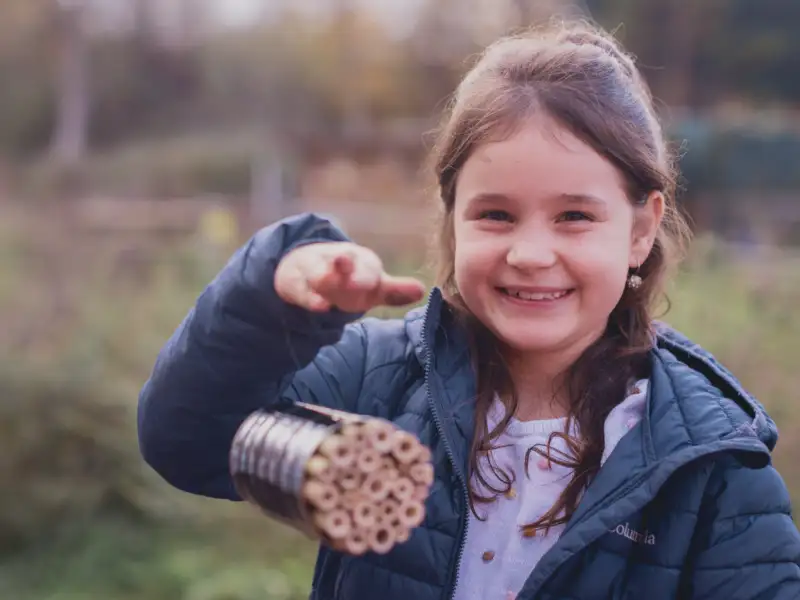 Ein Mädchen zeigt eine Nisthilfe für Insekten.
