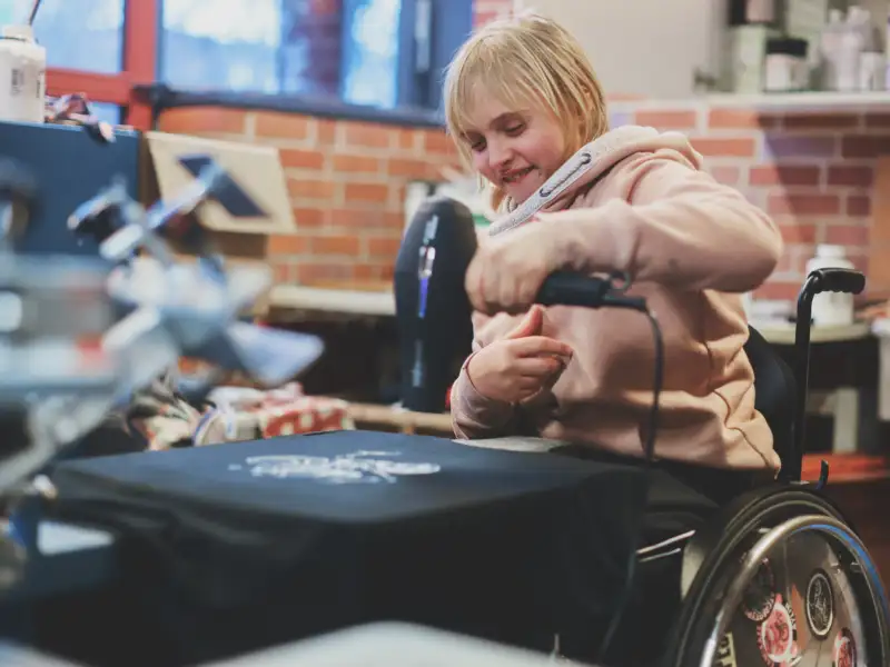 Junge Frau im Rollstuhl gestaltet ein T-Shirt