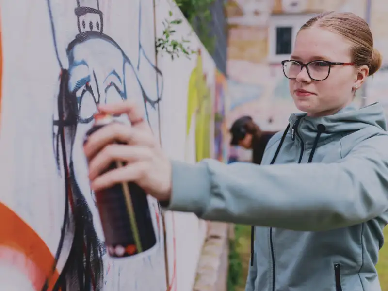 Eine Jugendliche sprüht Graffiti