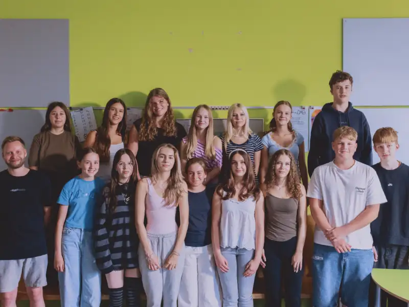 Gruppenbild von Jugendlichen und einem Erwachsenen in einem Klassenzimmer