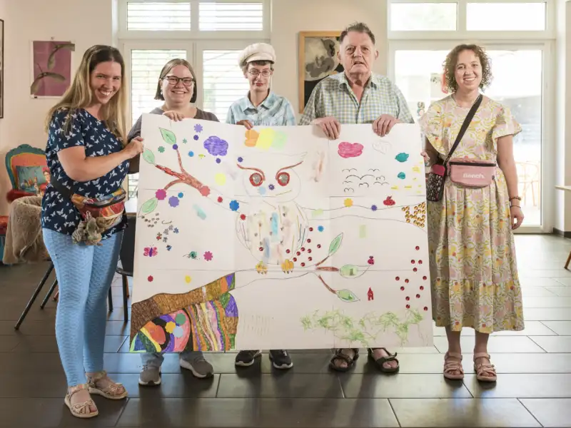 Fünf Personen stehen hinter einem großem, selbst gemalten Bild
