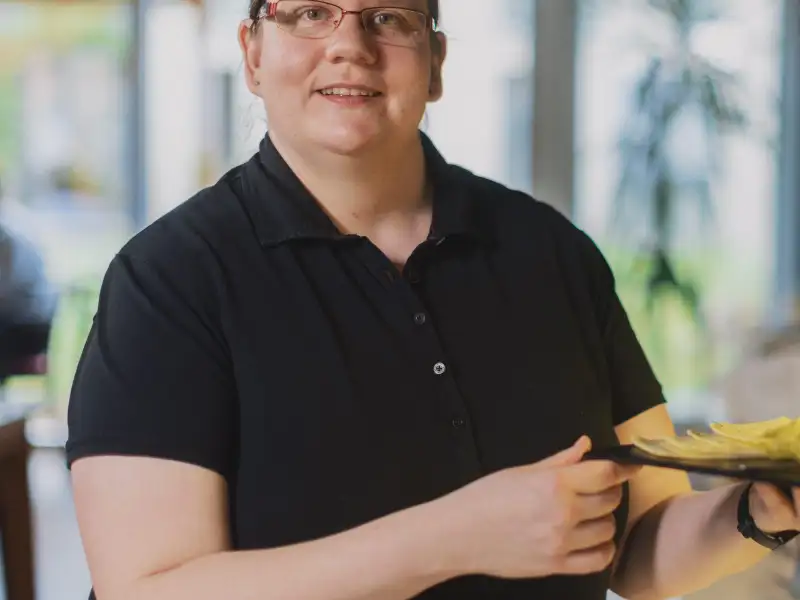 Eine junge Frau stellt einen Teller mit Obst in eine Vitrine.