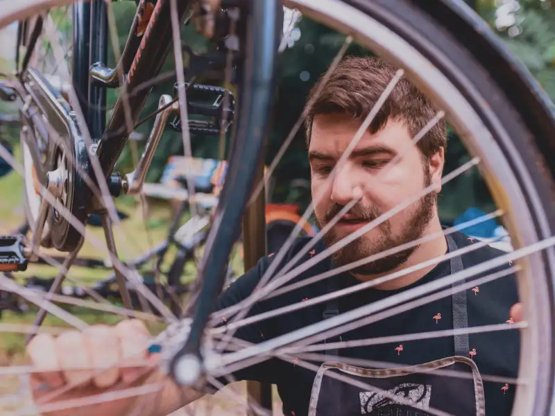 Ein junger Mann zieht mit einer Zange einen Fahrradreifen fest.