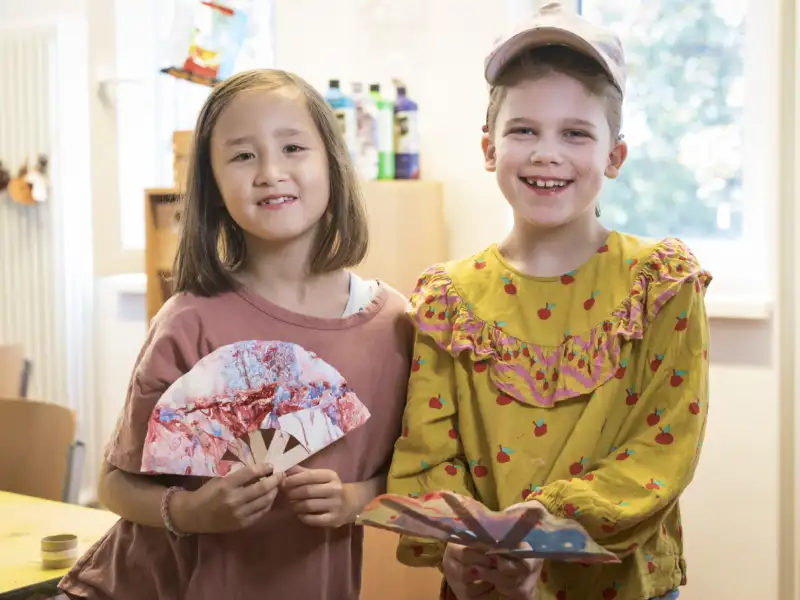 Ein Junge und ein Mädchen,das einen bunten Fächer zeigt