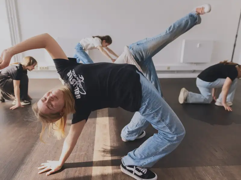 Jugendliche machen Breakdance-Bewegungen am Boden