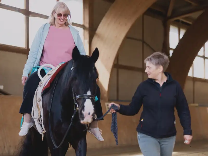 Eine Frau reitet auf einem Pferd, das von einer anderen Frau geführt wird