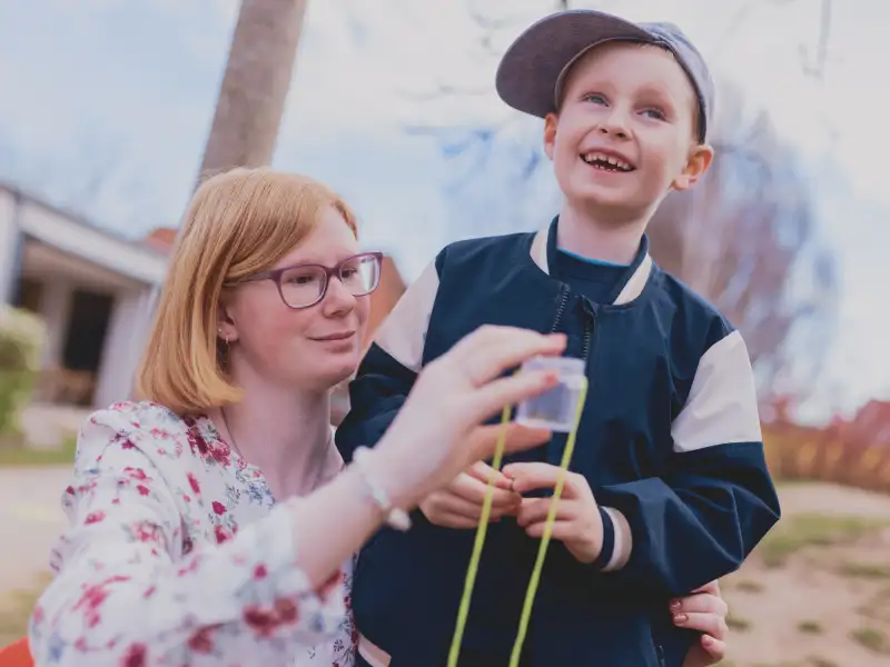 Eine junge Frau mit Downsyndrom spielt mit einem Jungen