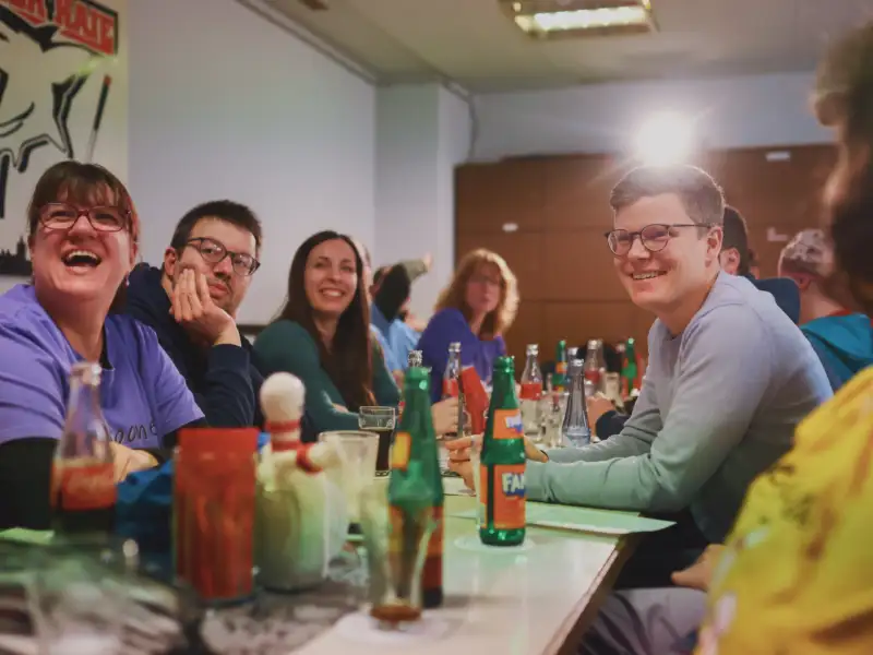 Eine Runde fröhlicher Menschen sitzt an einer Bierbank