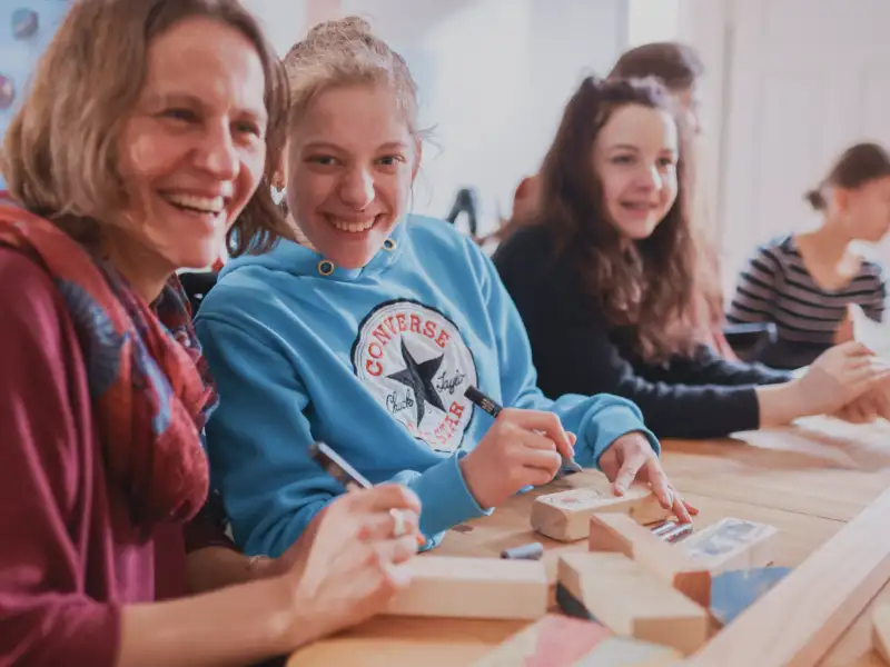 Menschen mit und ohne Behinderung an einem Tisch beim Basteln