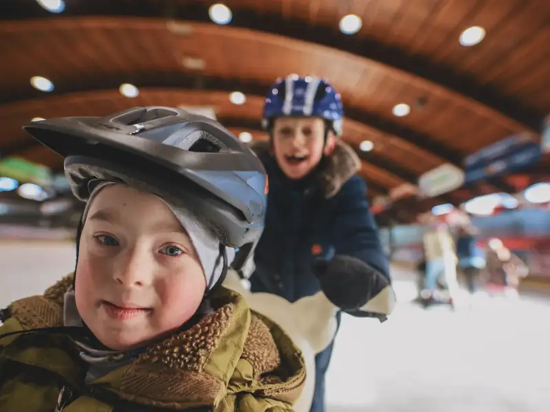 Zwei Jungs in der Eishalle, einer im Rollstuhl