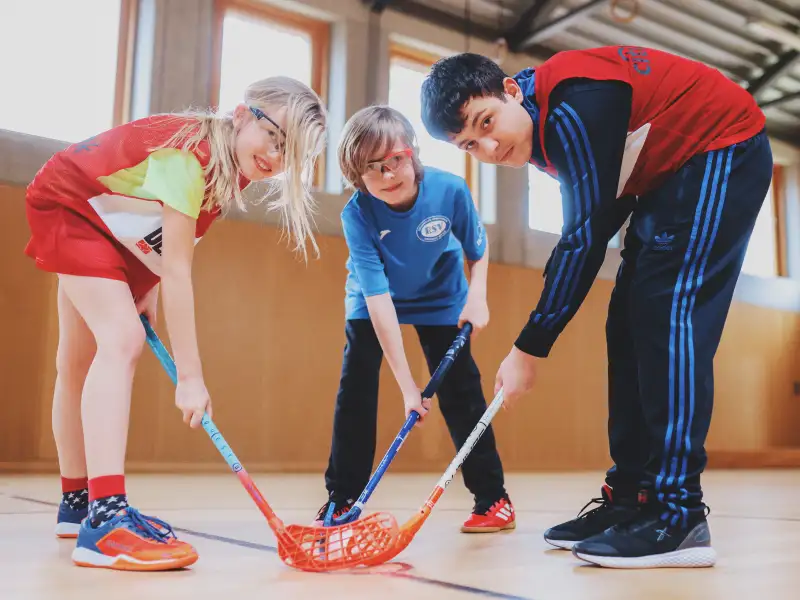 Drei Jugendliche beim Floorball-Spiel