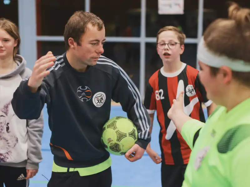 Jugendliche beim Ballspiel mit Trainer in der Halle