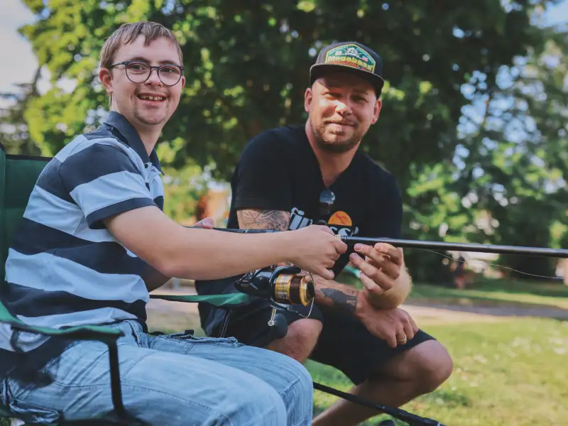Zwei Personen beim Angeln, einer davon mit Downsyndrom