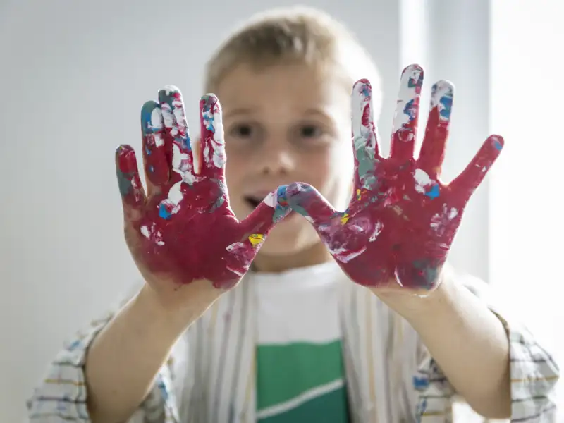 Ein Junge zeigt seine bunt bemalten Handflächen