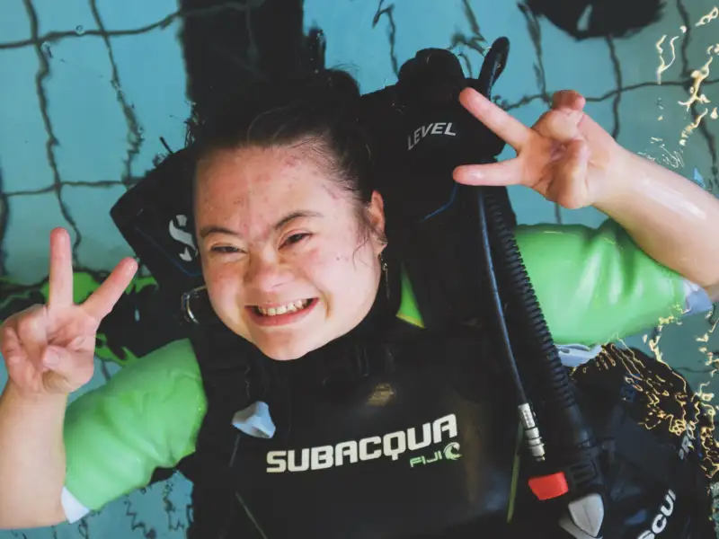 Mädchen mit Downsyndrom mit Tauchausrüstung im Wasser