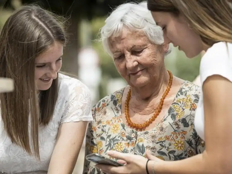 Zwei jüngere und eine ältere Frau schauen auf ein Smatphone