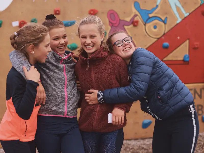Vier jugendliche Mädchen vor einer Boulder-Wand