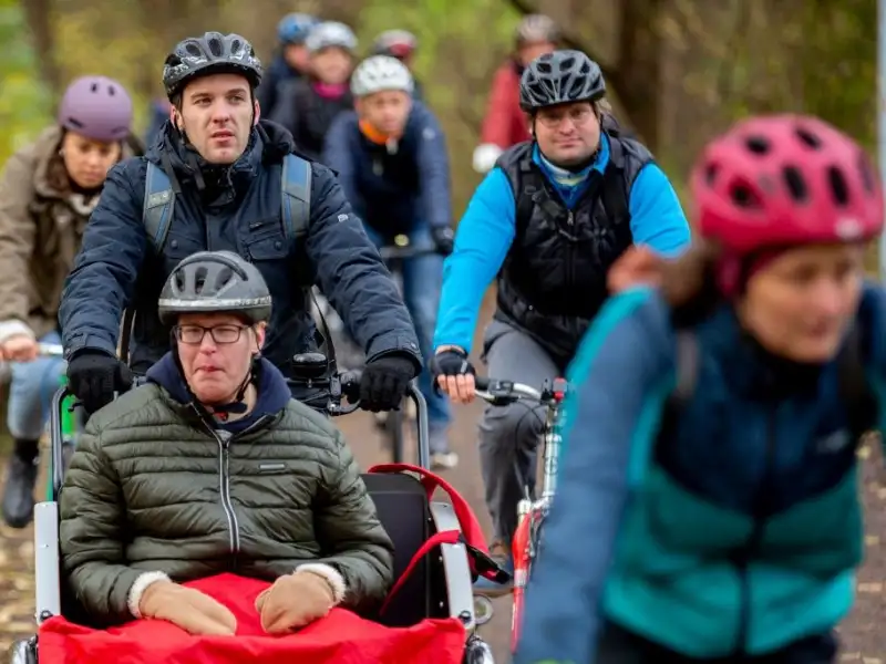Eine Gruppe Radler mit E-Rikscha im Wald