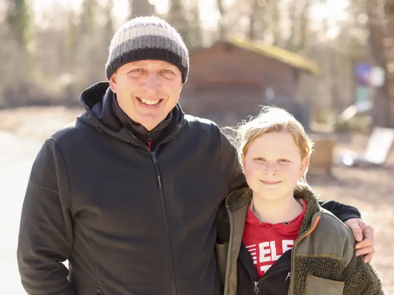 Ein Mann und ein Kind stehen lächelnd nebeneinander