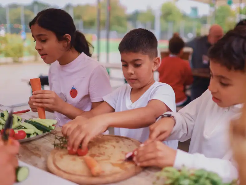 Drei Kinder an einem Buffet auf einem Sportplatz