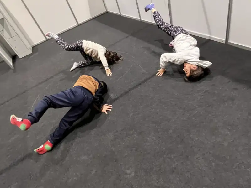 Drei Kinder üben Breakdance-Moves am Boden.