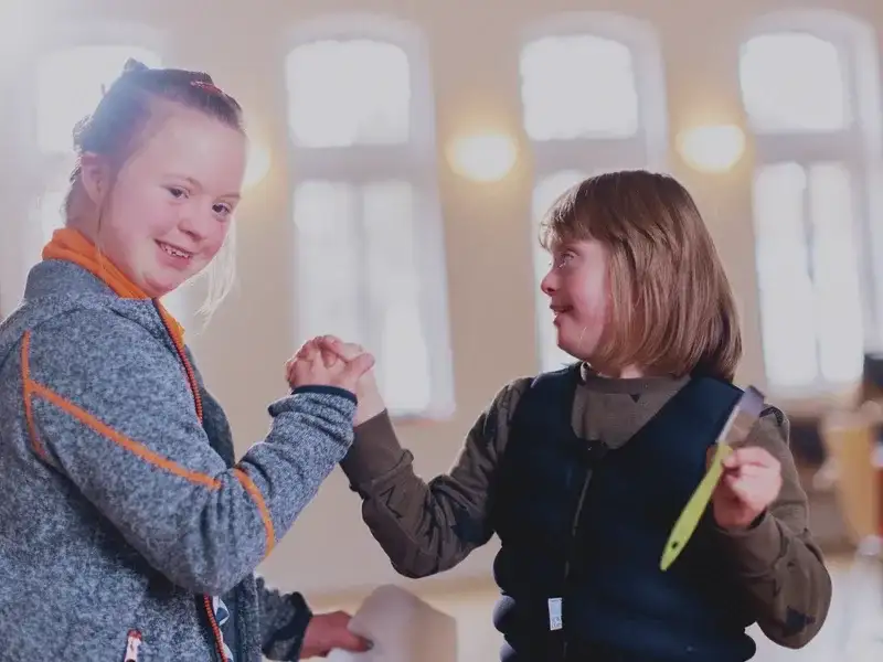 Zwei kleine Mädchen halten sich an den Händen.