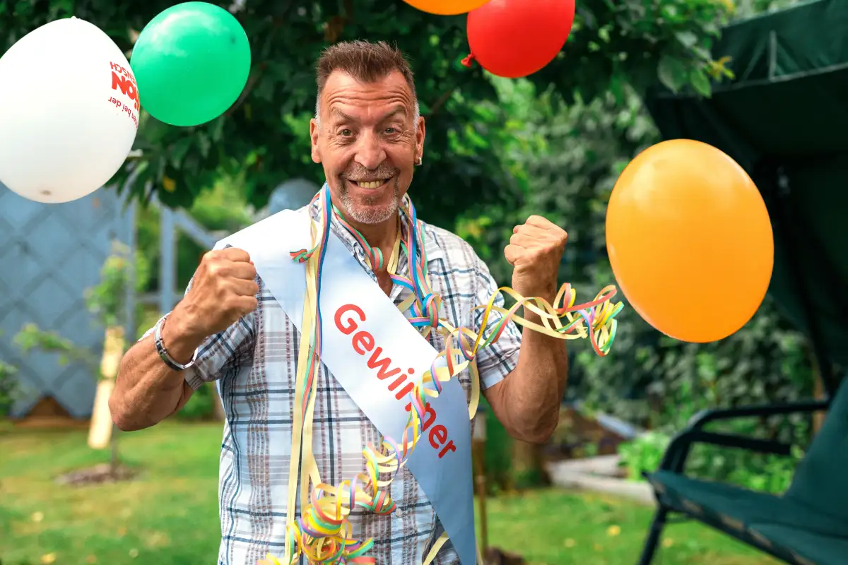 Ein Mann der begeistert über seinen Gewinn die Fäuste nach oben streckt.