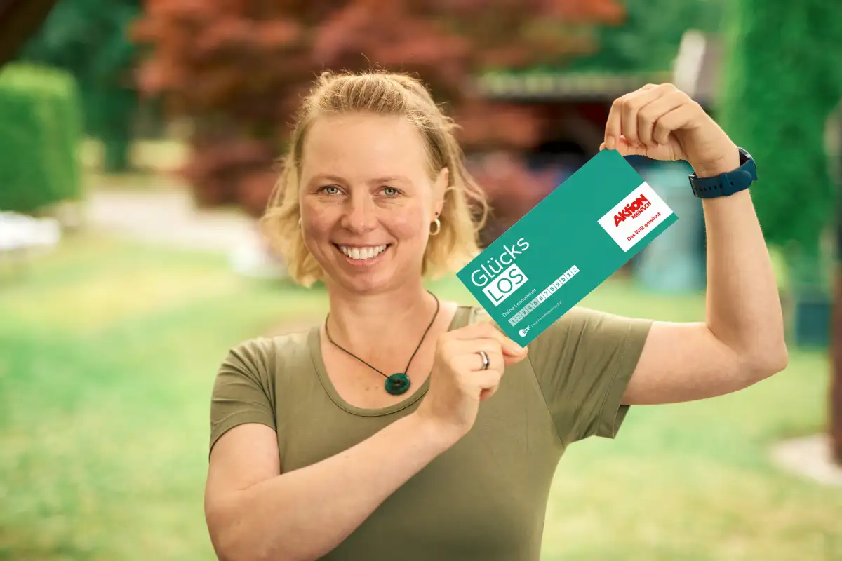 Junge Frau hält freudestrahlend ihr Glückslos in der Hand und freut sich über ihren Gewinn.