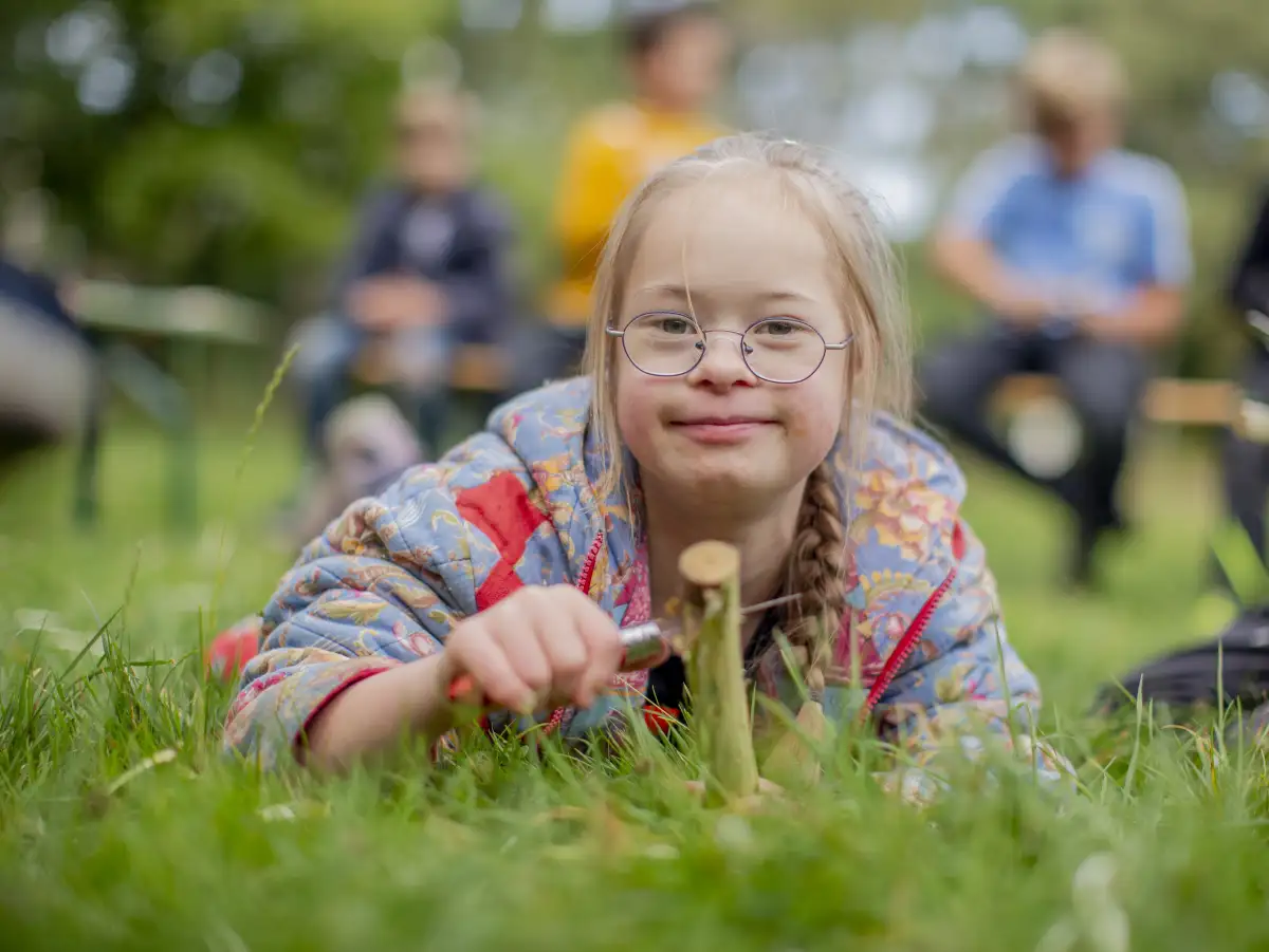 Mädchen mit Downsyndrom hat Spaß beim Schnitzen im Wald-Erlebnis-Projekt