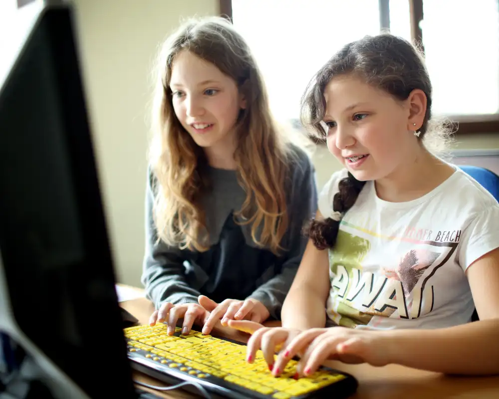 Zwei Mädchen tippen etwas in den Computer.