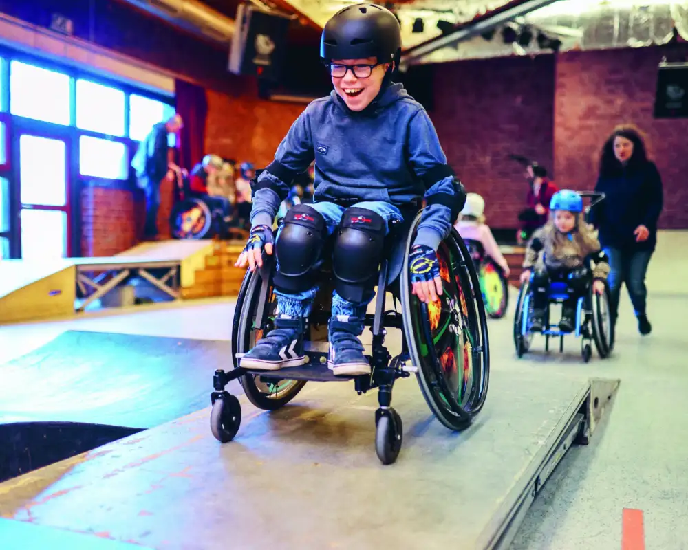 Ein Junge im Rollstuhl fährt über eine Skatebahn