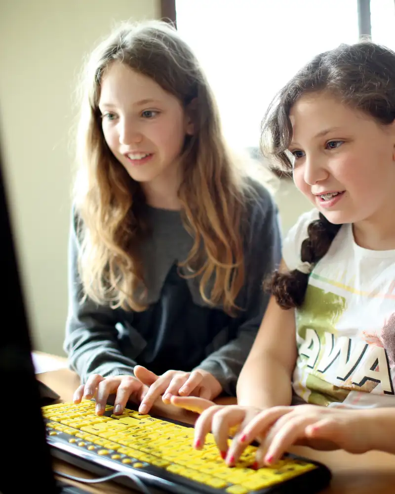 Zwei Mädchen tippen etwas in den Computer.