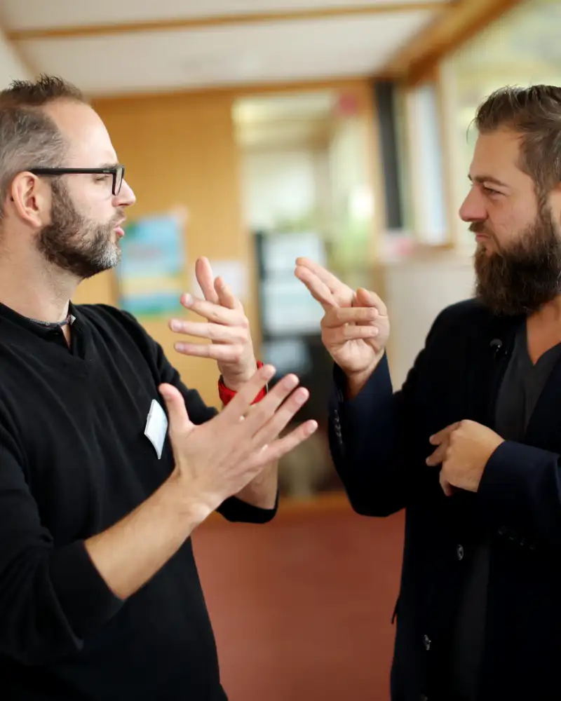 Zwei Menschen unterhalten sich in Gebärdensprache.