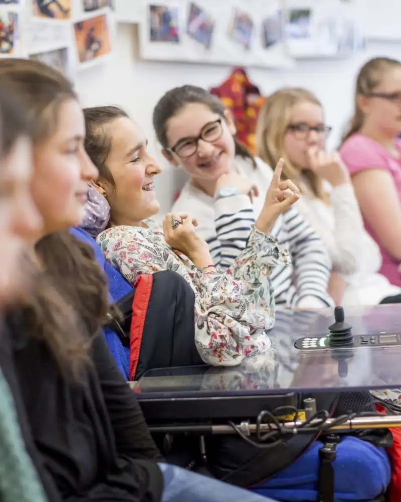 Schülerinnen und Schüler einer inklusiven Klasse sitzen zusammen in einem Stuhlkreis.