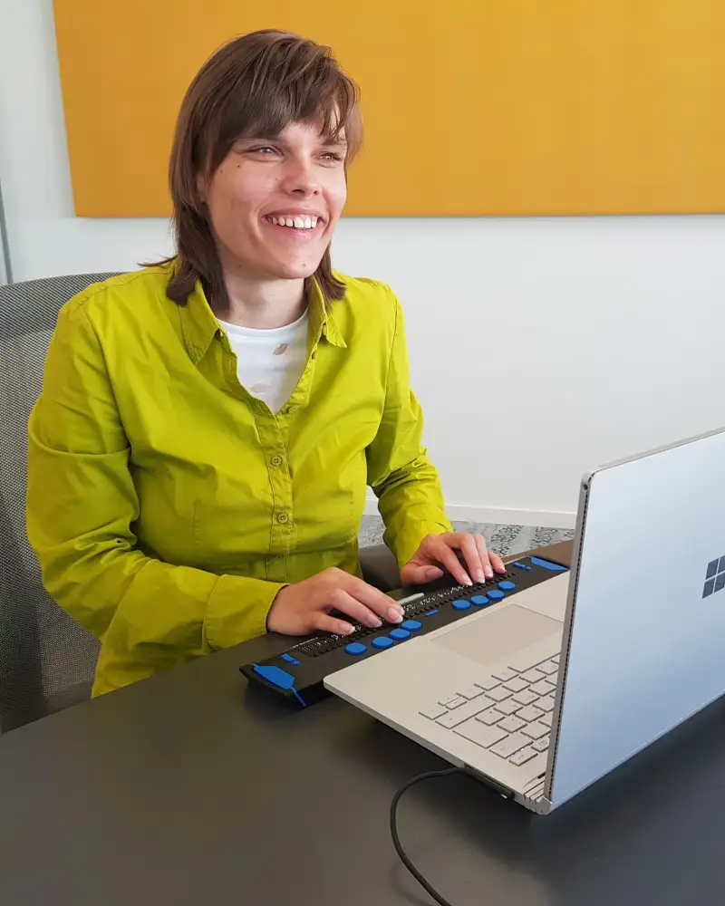 Franziska Sgoff arbeitet mit einer Braillezeile an einem Laptop-Computer.