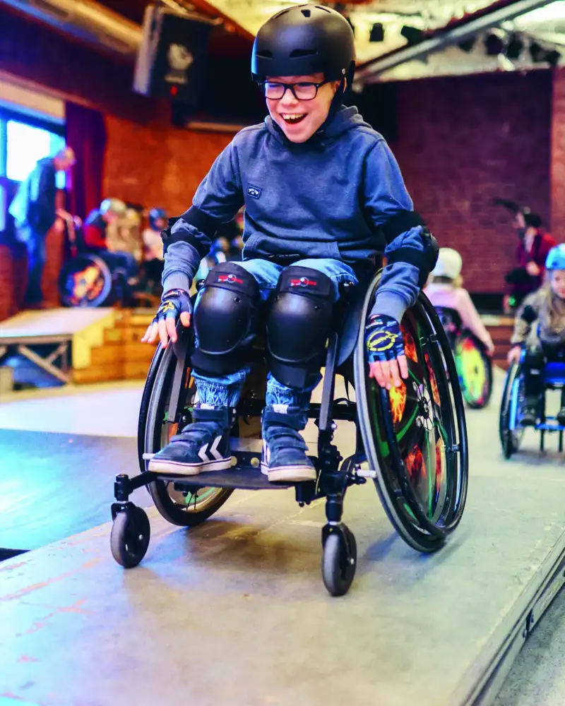 Ein Junge im Rollstuhl fährt über eine Skatebahn