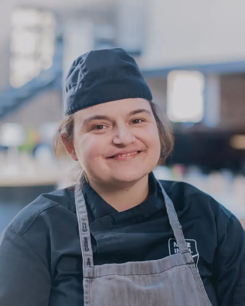 Eine junge Frau in Arbeitskleidung lächelt in die Kamera