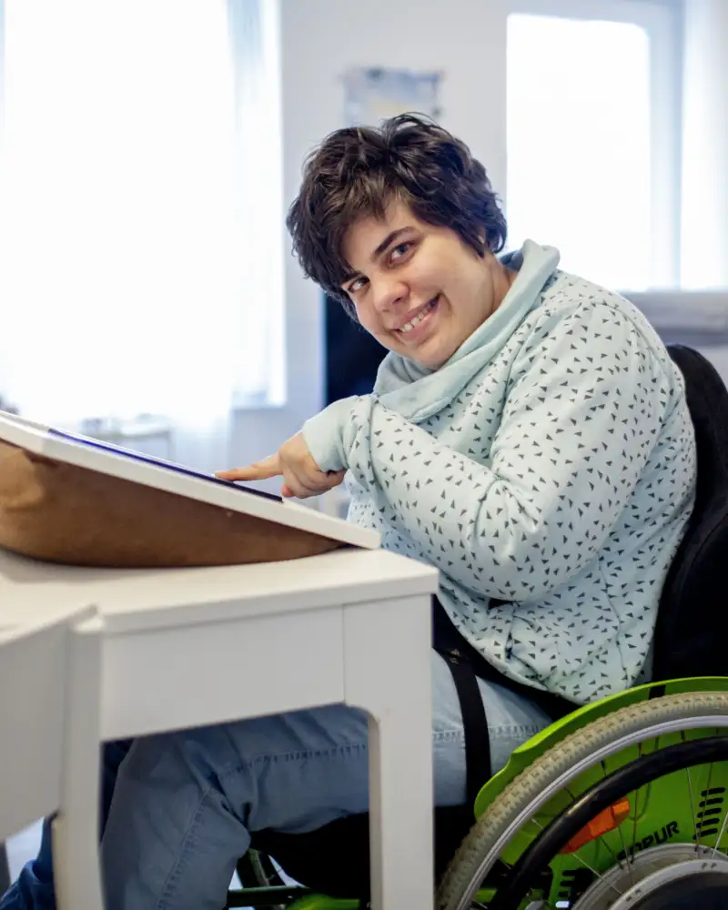 Eine Frau im Rollstuhl bedient zu Hause ein Tablet