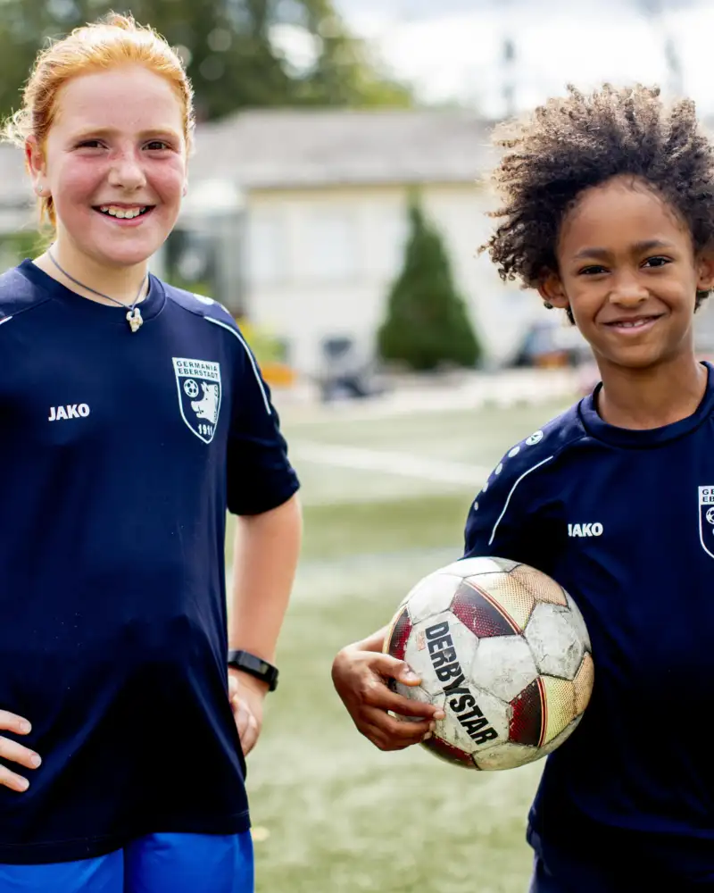 Zwei Jugendliche in blauen Trikots und einem Fußball