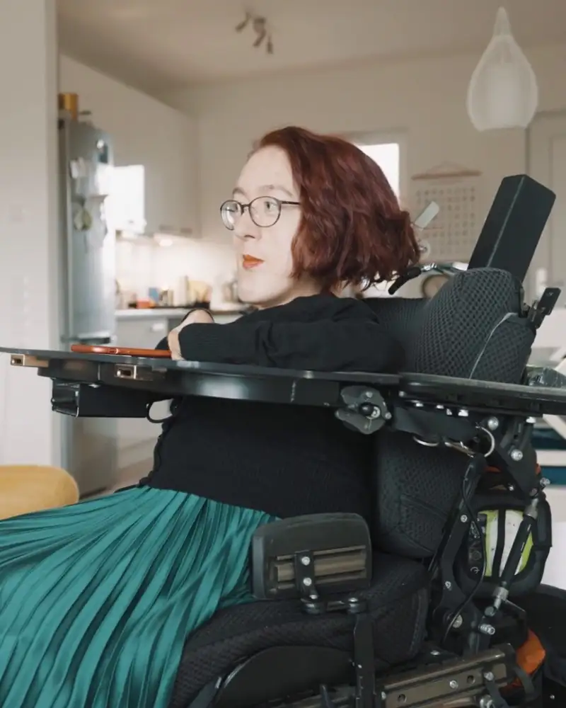 Zwei junge Frauen sitzen sich in ihren elektrischen Rollstühlen gegenüber und schauen sich an.